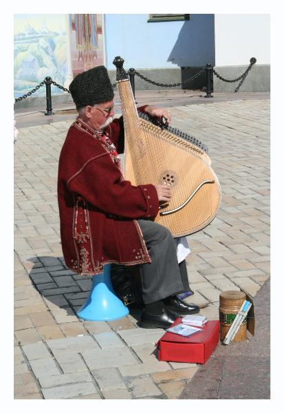 A guy in folk dress, playing a folk instrument, singing a folk song, and sitting on a bright blue plastic thing...  We thought he was cool.